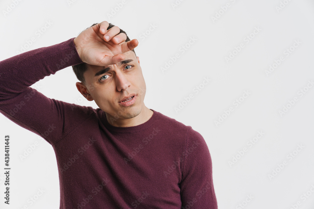 Young brunette man wiping his forehead and looking at camera Young brunette man wiping his forehead and looking at camera