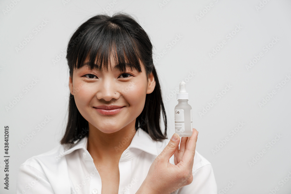 Young asian woman smiling while showing facial serum Young asian woman smiling while showing facial serum