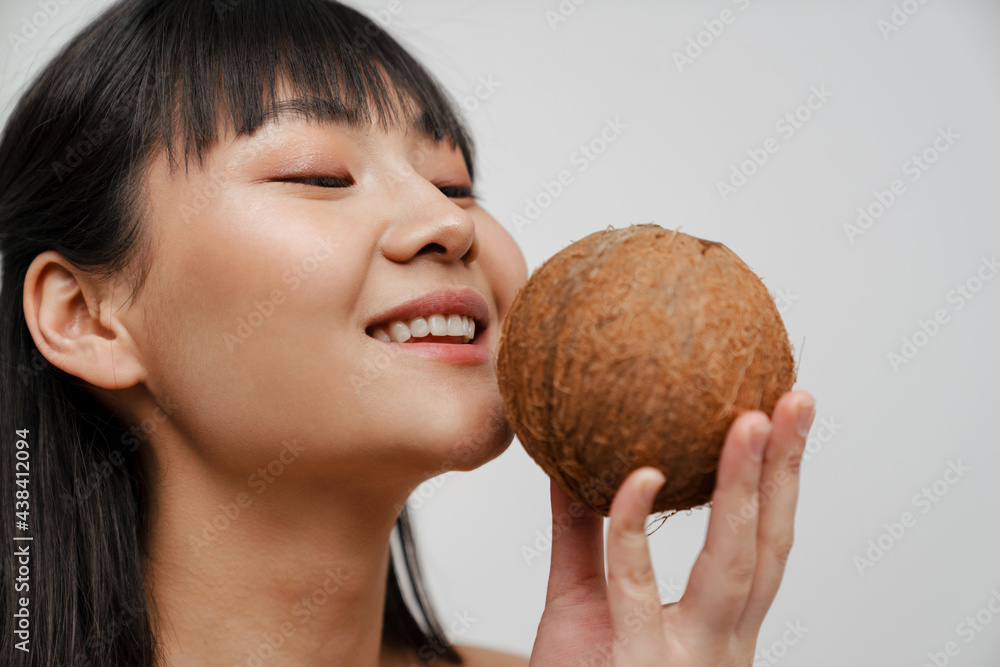 Young asian shirtless woman smiling while posing with coconut Young asian shirtless woman smiling while posing with coconut