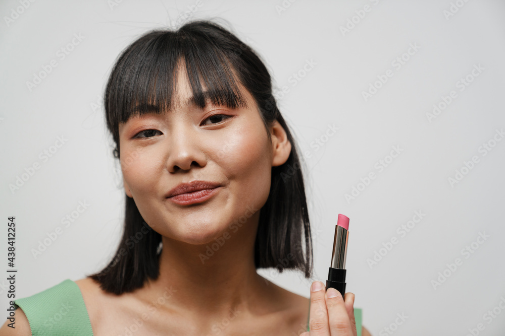Young asian brunette woman posing and showing lipstick Young asian brunette woman posing and showing lipstick
