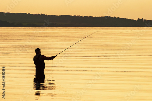 Lone fly fisherman by the sea in the sunrise