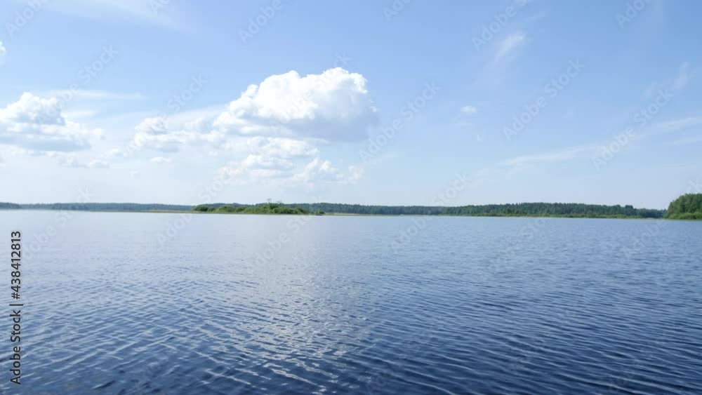 Beautiful drone flight over a river. Flying over a blue lake on a sunny day. Cloudy sky reflecting from smooth water. Wild nature. Drone flies extremely closely to a river with a smooth water surface. Beautiful drone flight over a river. Flying over a blue lake on a sunny day. Cloudy sky reflecting from smooth water. Wild nature. Drone flies extremely closely to a river with a smooth water surface.