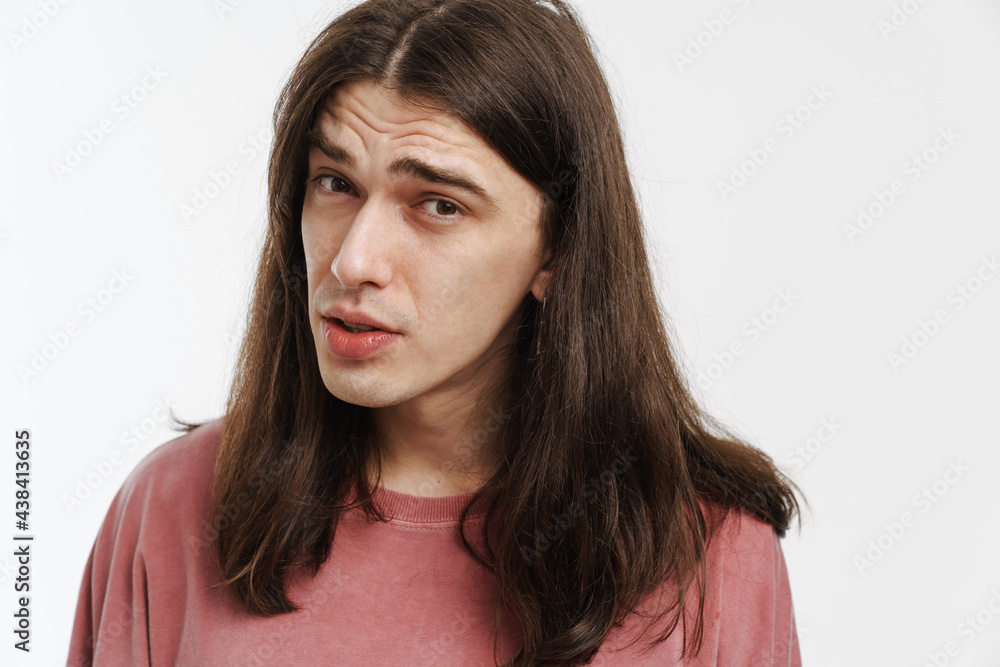 Young confused man with long hair posing and looking at camera Young confused man with long hair posing and looking at camera