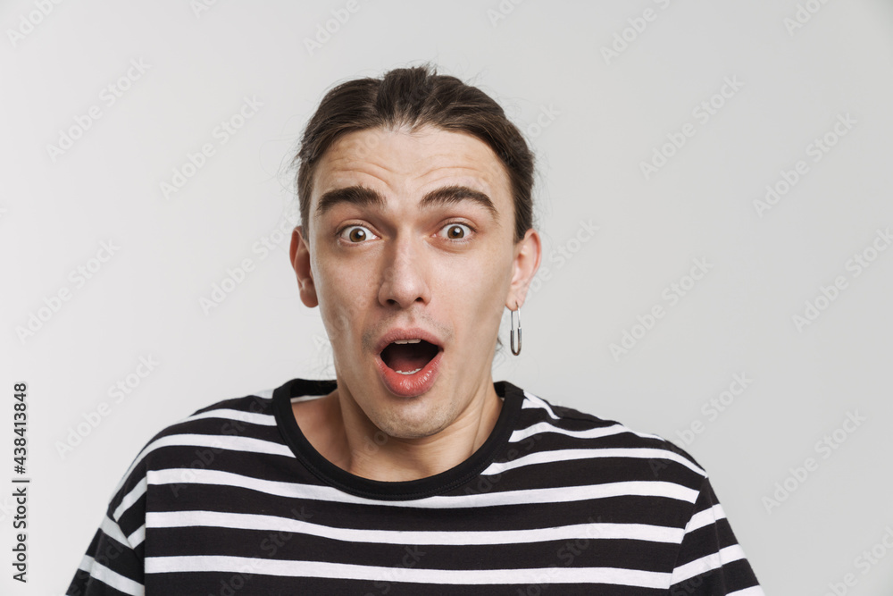 Young white man with earring expressing surprise at camera Young white man with earring expressing surprise at camera