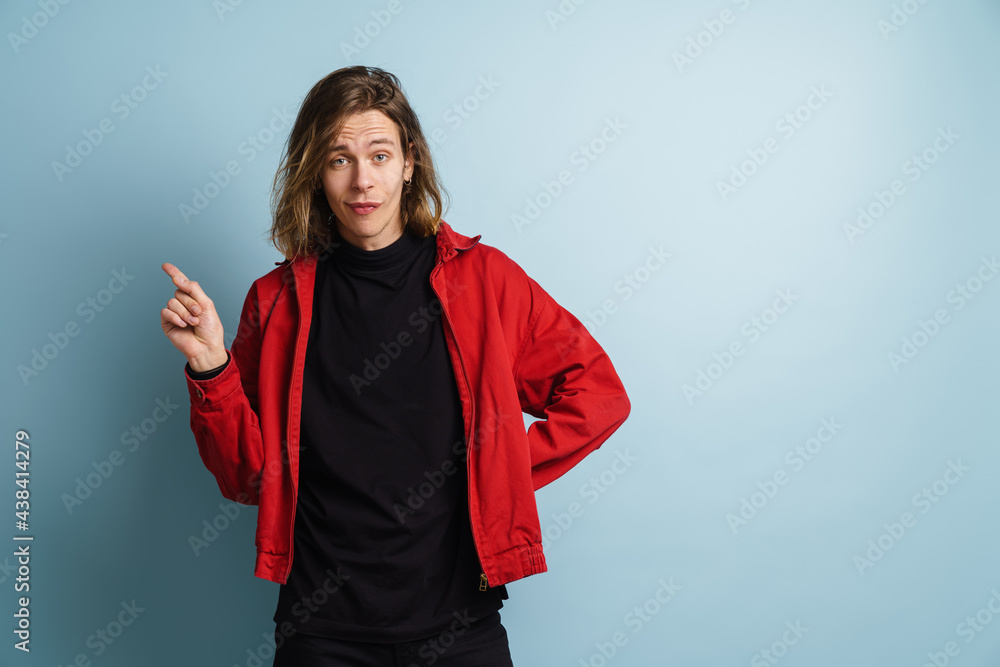 Young white man looking at camera and pointing finger aside Young white man looking at camera and pointing finger aside
