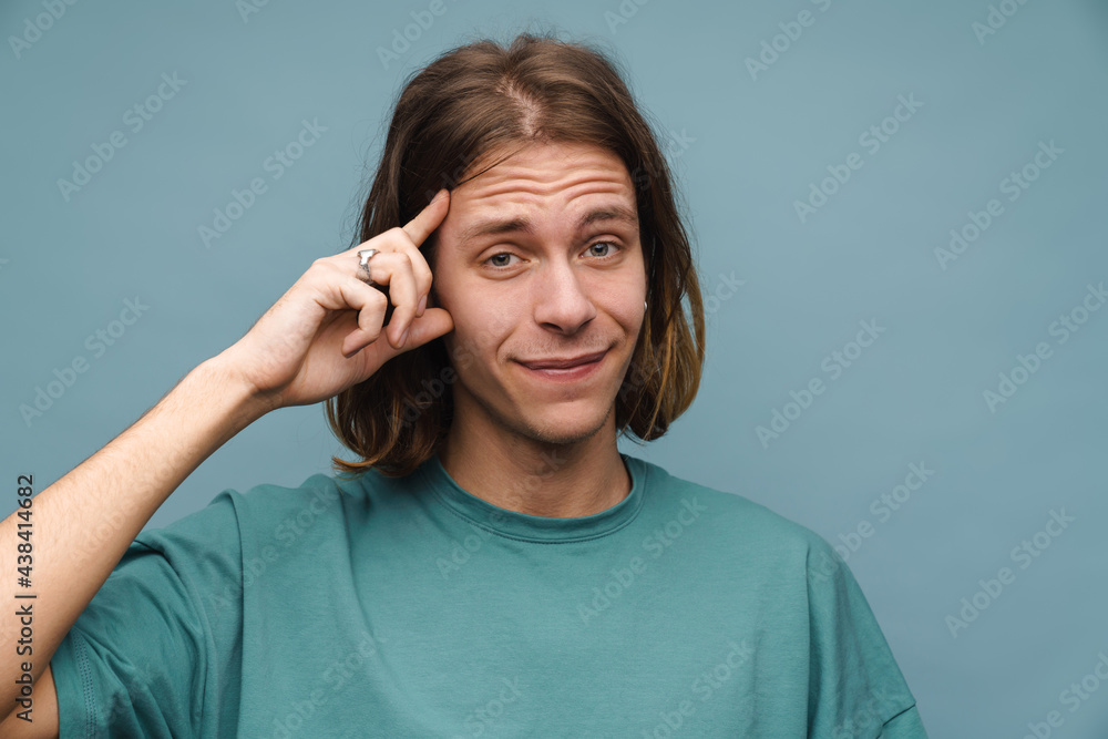 Young white man smiling and pointing finger at his head Young white man smiling and pointing finger at his head