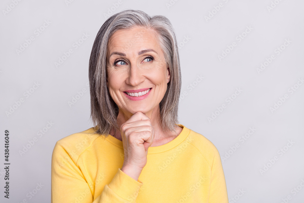 Photo of cute dreamy mature lady wear yellow clothes arm chin looking empty space smiling isolated grey color background Photo of cute dreamy mature lady wear yellow clothes arm chin looking empty space smiling isolated grey color background