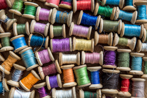 The background is made of colorful threads on wooden vintage reels. Skeins of colored thread. Top view.
