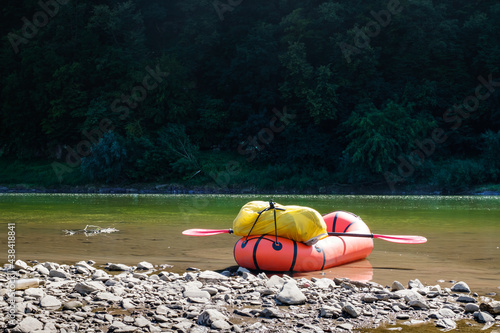 Orange packraft rubber boat with backpack on a river photo