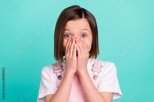 Photo of happy amazed shocked little girl hold hands cover face mouth isolated on teal color background