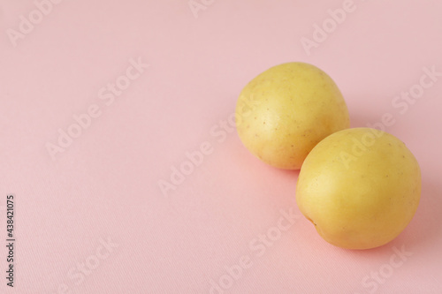 Young potato on pink background, space for text