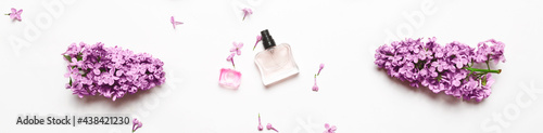 Spring flowers. Floral scent concept. elegant Perfume bottle with lilac flowers over white background. Top view, flat layer. Banner