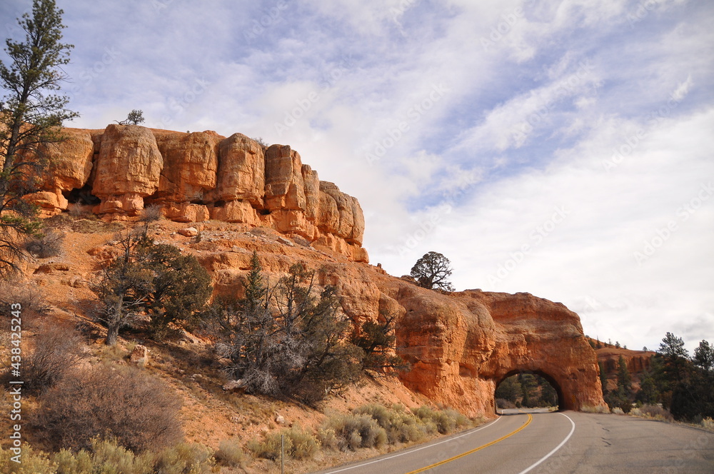Pan view of road through huge rocky landscape and cliffs under cloudy sky in Paunsaugunt Plateau of Bryce Canyon National Park, USA Pan view of road through huge rocky landscape and cliffs under cloudy sky in Paunsaugunt Plateau of Bryce Canyon National Park, USA