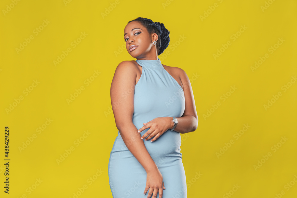 beautiful smiling african american girl in a blue dress, with pigtails hair rejoices on a yellow background beautiful smiling african american girl in a blue dress, with pigtails hair rejoices on a yellow background
