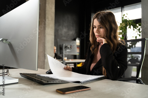 Female designer in office working on architects project. Business woman, view architectural drawings in office behind desk. Architect engineer works with technical drawings. Creator worke in studio photo