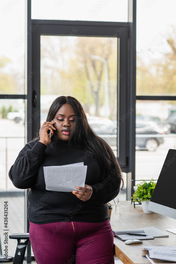 african american plus size businesswoman talking on smartphone and holding documents.