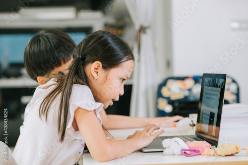 Asian girl is reading out loud while studying online with laptop at home