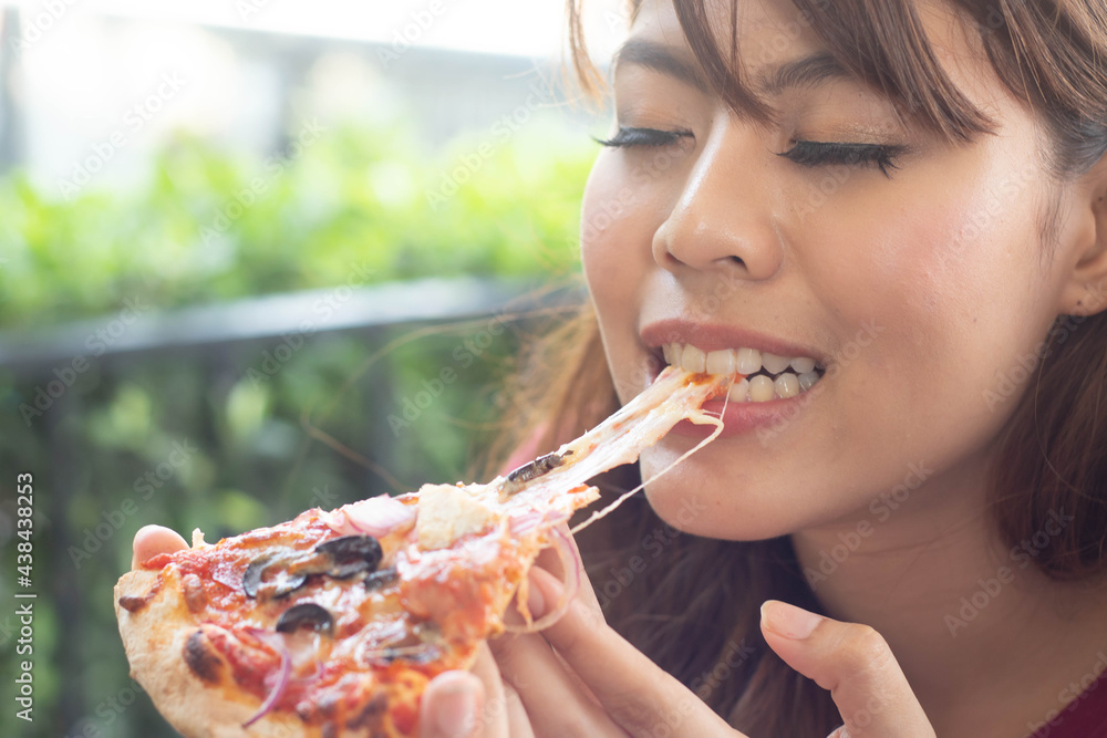 Beautiful young woman eating a piece of Italian pizza in cafe, Her feeling enjoyment. Beautiful young woman eating a piece of Italian pizza in cafe, Her feeling enjoyment.
