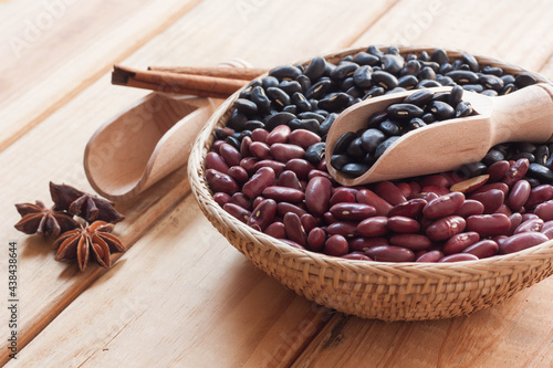 Black beans and red beans in basket on wood background.