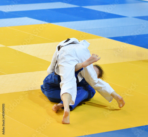 Two Girls judoka in kimono compete on the tatami 