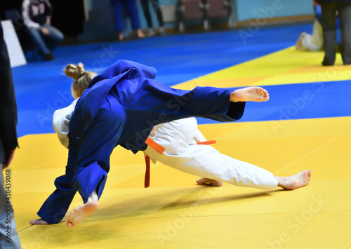 Two Girls judoka in kimono compete on the tatami 