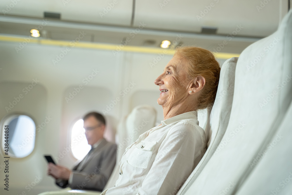 Fototapeta premium Passenger elderly woman seated on the plane in flight,Travel concept.