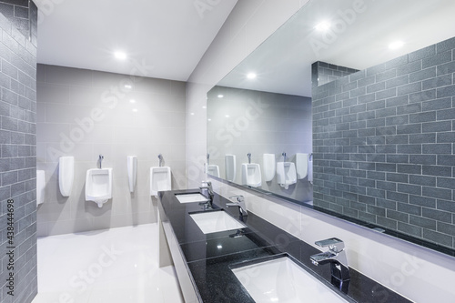 Contemporary public Interior of bathroom with sink basin faucet lined up with big mirror and public toilet urinals Modern design. photo