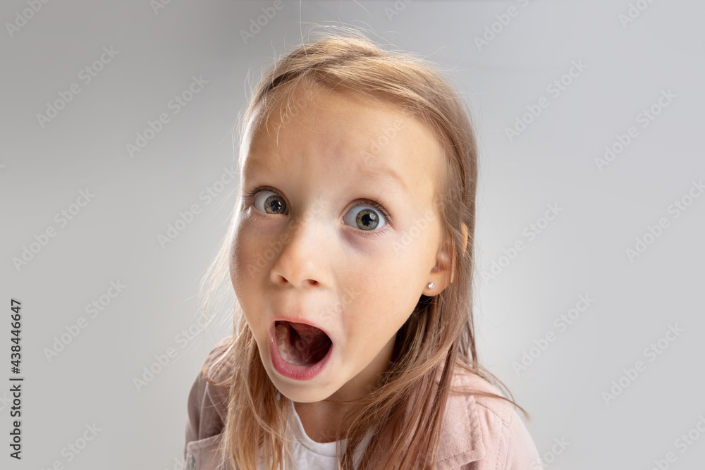 Beautiful little girl looking suprised on pastel studio background Beautiful little girl looking suprised on pastel studio background