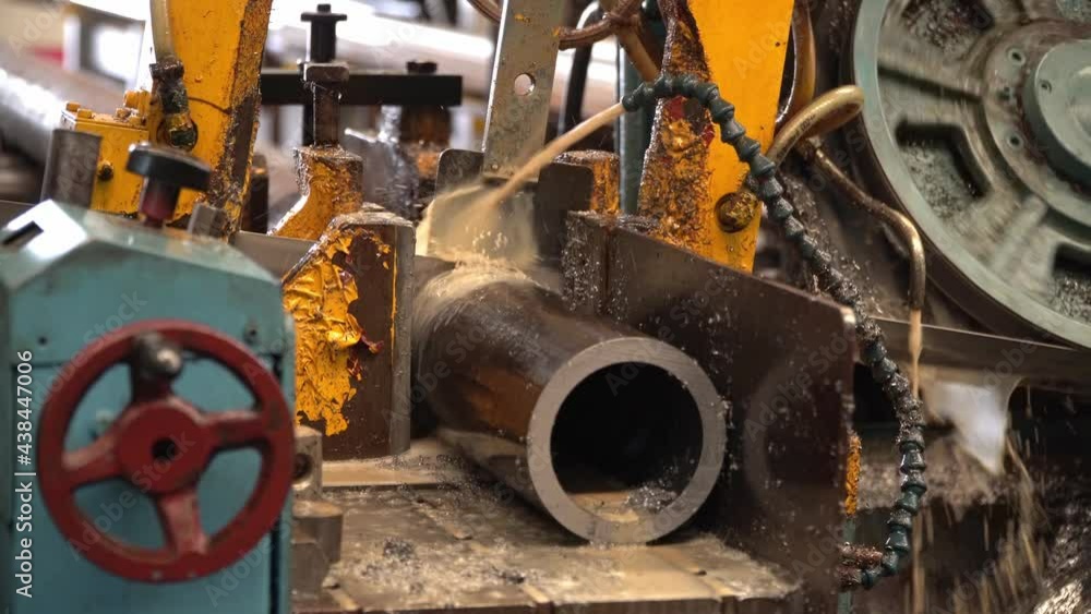 Industrial band saw, cutting metal pipe, coolant in yellow scene, industrial tools Industrial band saw, cutting metal pipe, coolant in yellow scene, industrial tools