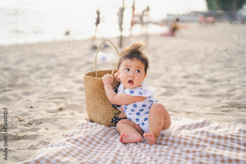 baby in white dress on the beach with relaxing and the wind blows in evening time and sit on canvas