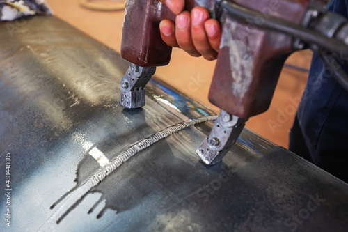 Fotografie Male worker test steel pipeline butt weld carbon background white contrast