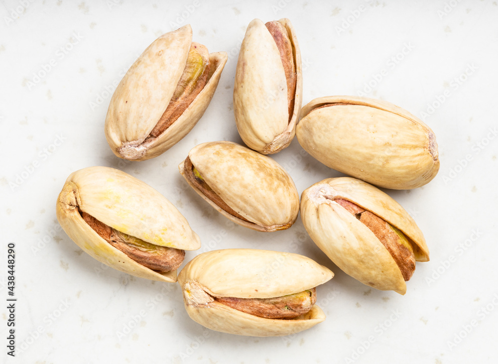 several raw ripe pistachio nuts close up on gray