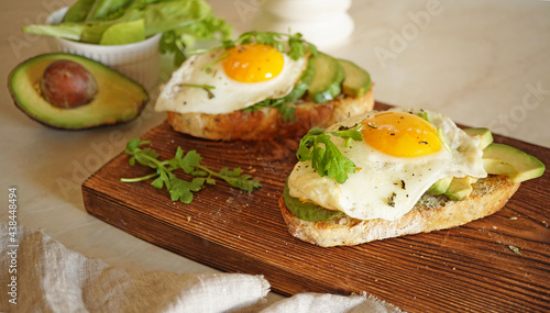 sandwich with egg and avocado on a wooden board and one in the background