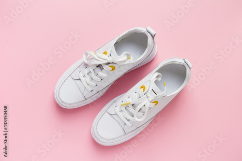 Pair of fashion white sneakers shoes on a pink isolated background. Street style shoes.