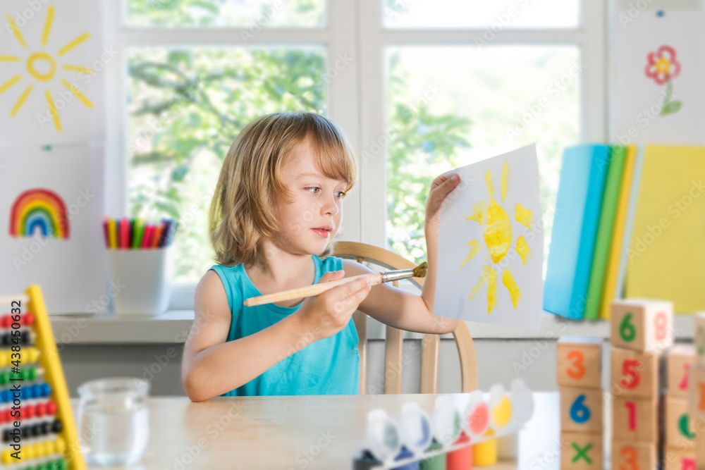 Funny beautiful happy child boy draws laughing with paint. Kid shows drowing of sun. Selective focus. Funny beautiful happy child boy draws laughing with paint. Kid shows drowing of sun. Selective focus.