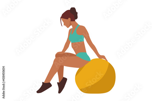 Sporting slim young woman in green suit sits on a yellow ball for fitness