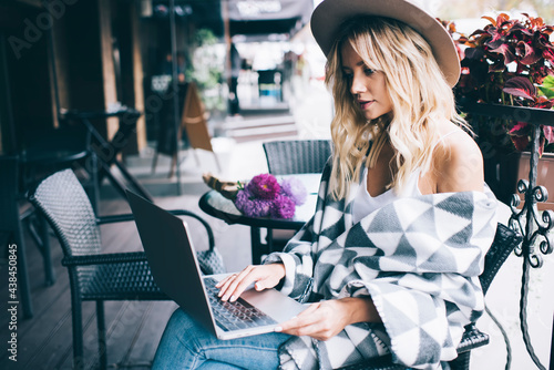 Millennial fashion blogger using laptop computer for networking in social media during leisure in cafe, young freelancer browsing web information on modern netbook connecting to 4g wireless