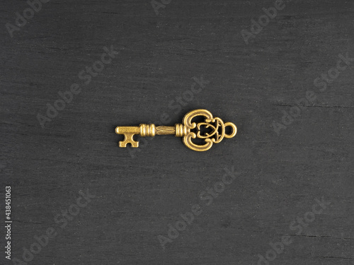 Bronze antique small key on black wooden background © zah108