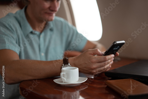 Successful young businessman traveler drinks coffee during flight in private jet 