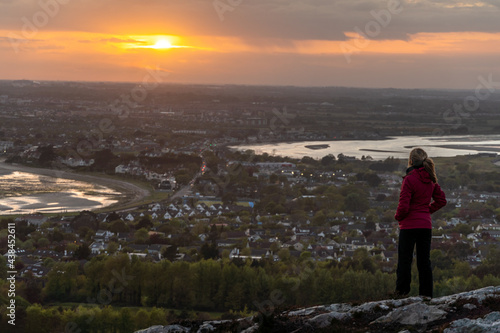 woman wearing pink jacket, back on top of mountain, admiring sunset in Hoth Ireland