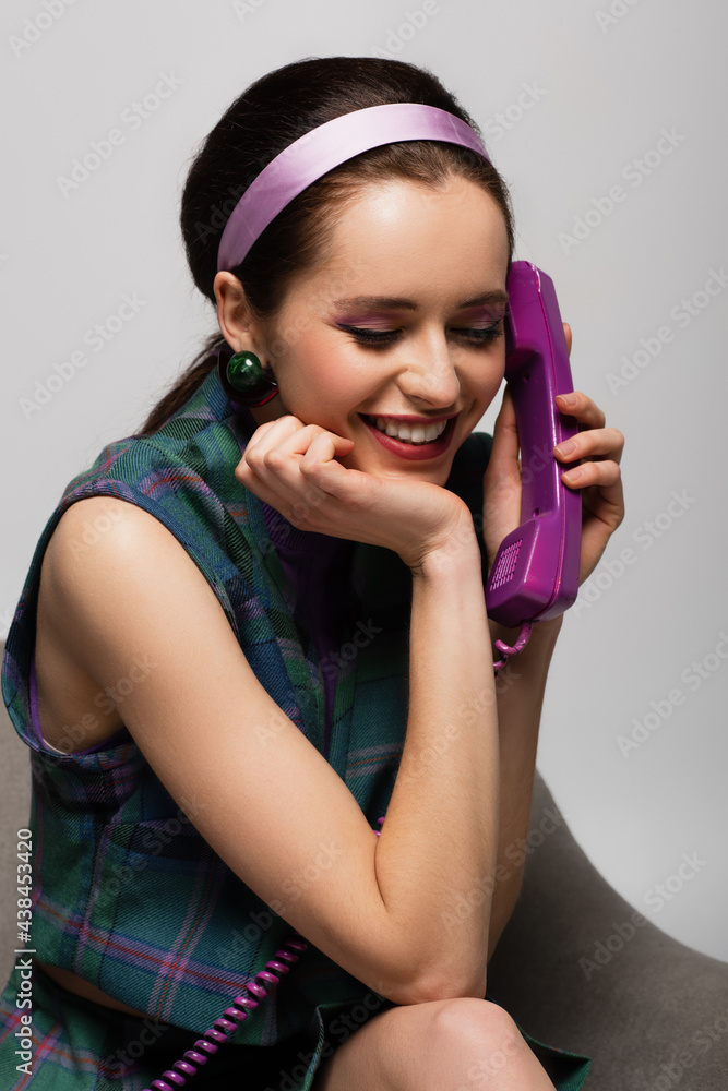 joyful young woman talking on retro phone isolated on grey. joyful young woman talking on retro phone isolated on grey.