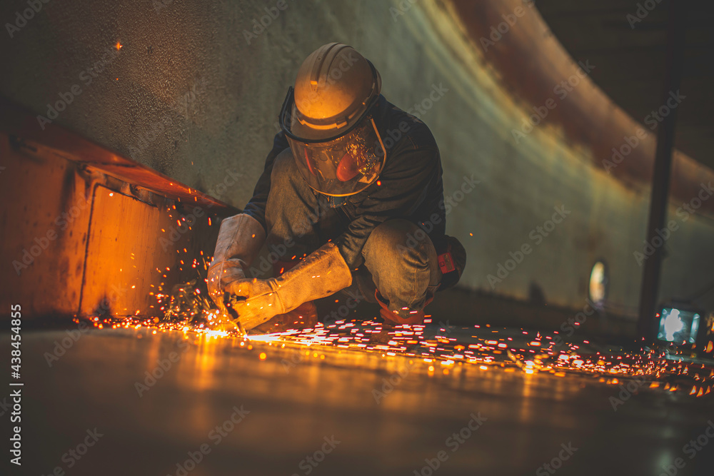 Male worker metal cutting spark on tank bottom steel plate with flash of cutting light close up wear protective gloves and mask Male worker metal cutting spark on tank bottom steel plate with flash of cutting light close up wear protective gloves and mask