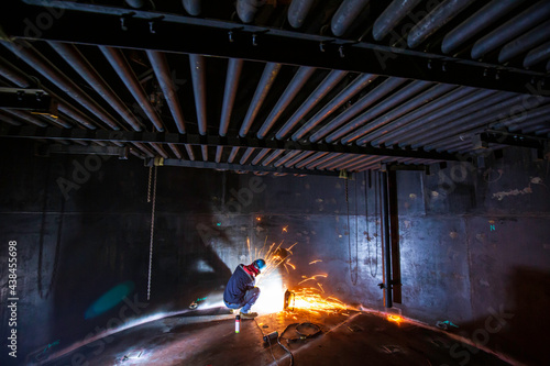 Male worker grinding on steel plate with flash of sparks close up wear protective gloves