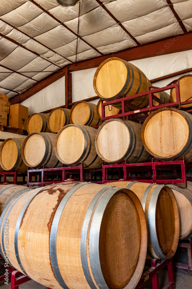 Landscape photo of racks of wine aging in barrels in barn of small local winery in California