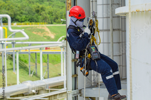 Male worker rope access height safety inspection of thickness storage oil and gas tank
