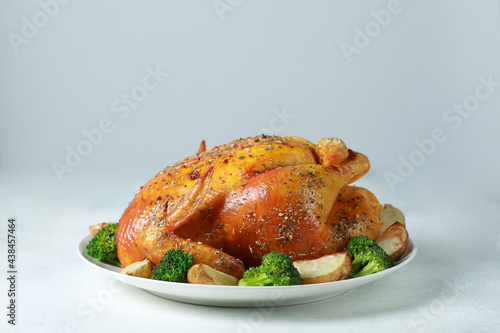 Fried chicken with a golden crust with broccoli and potatoes on a white plate on a white background. Fried poultry with spices and vegetables. Background image for advertising, copy space