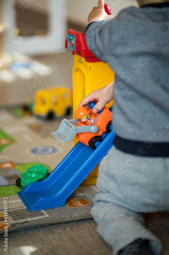 mains d'un petit garçon qui joue avec un tracteur en plastique photo