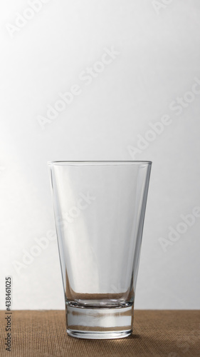 Empty glass vase on a wooden base. Vertical.