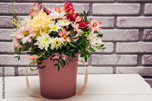 Delicate bouquet of different flowers in pink packaging. Square photo close-up