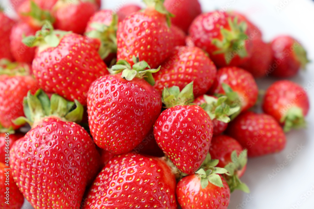 Fresh red strawberries with leaves on a white plate. Ripe strawberry for background Fresh red strawberries with leaves on a white plate. Ripe strawberry for background